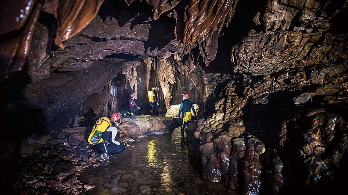 Un grupo de turistas sigue el curso de aguas de la Cueva de Valporquero, lo mejor del turismo activo nacional. | GUHEKO