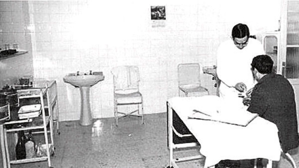 Un practicante haciendo una cura en una casa de socorro en los años setenta.