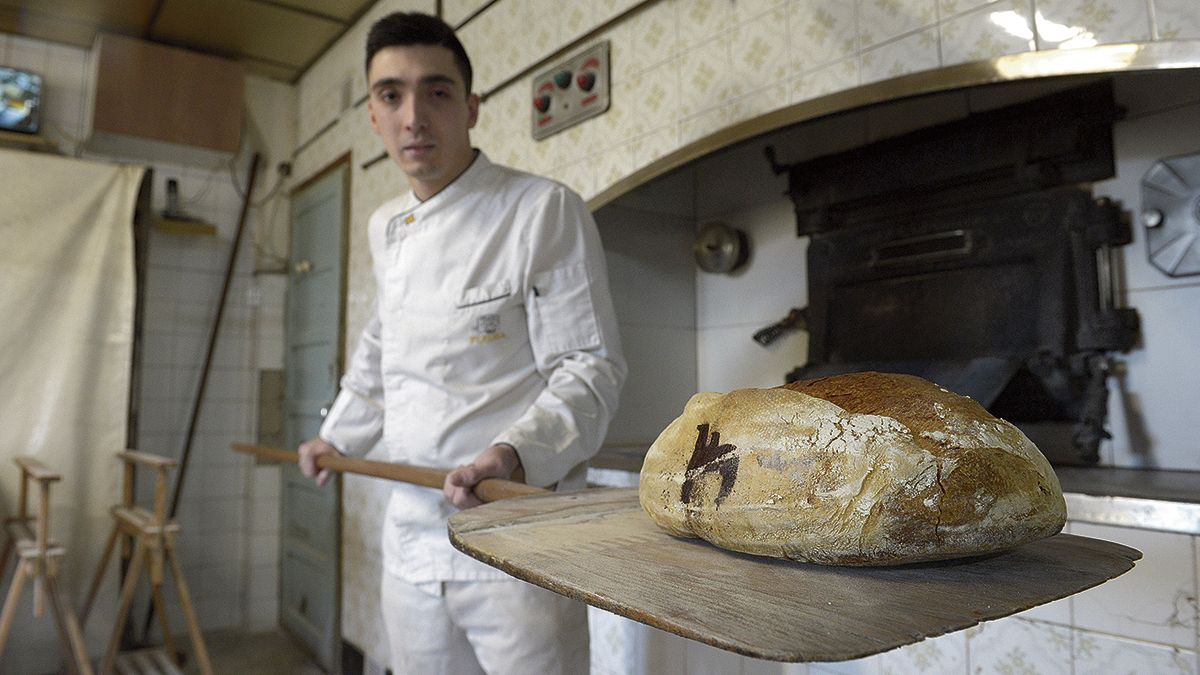 Daniel, a la puerta del horno de leña, con la hogaza de masa madre igual a la que dio el Campeonato de España de Panadería Artesana. | MAURICIO PEÑA