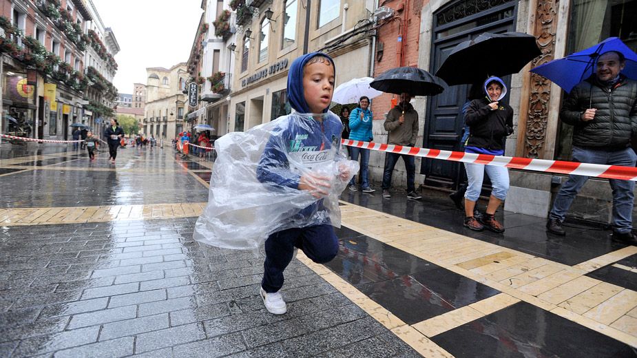 Un niño participa, con la cabeza bien tapada y el chubasquero puesto, en la última edición de los 10 kilómetros Ciudad de León. | DANIEL MARTIN