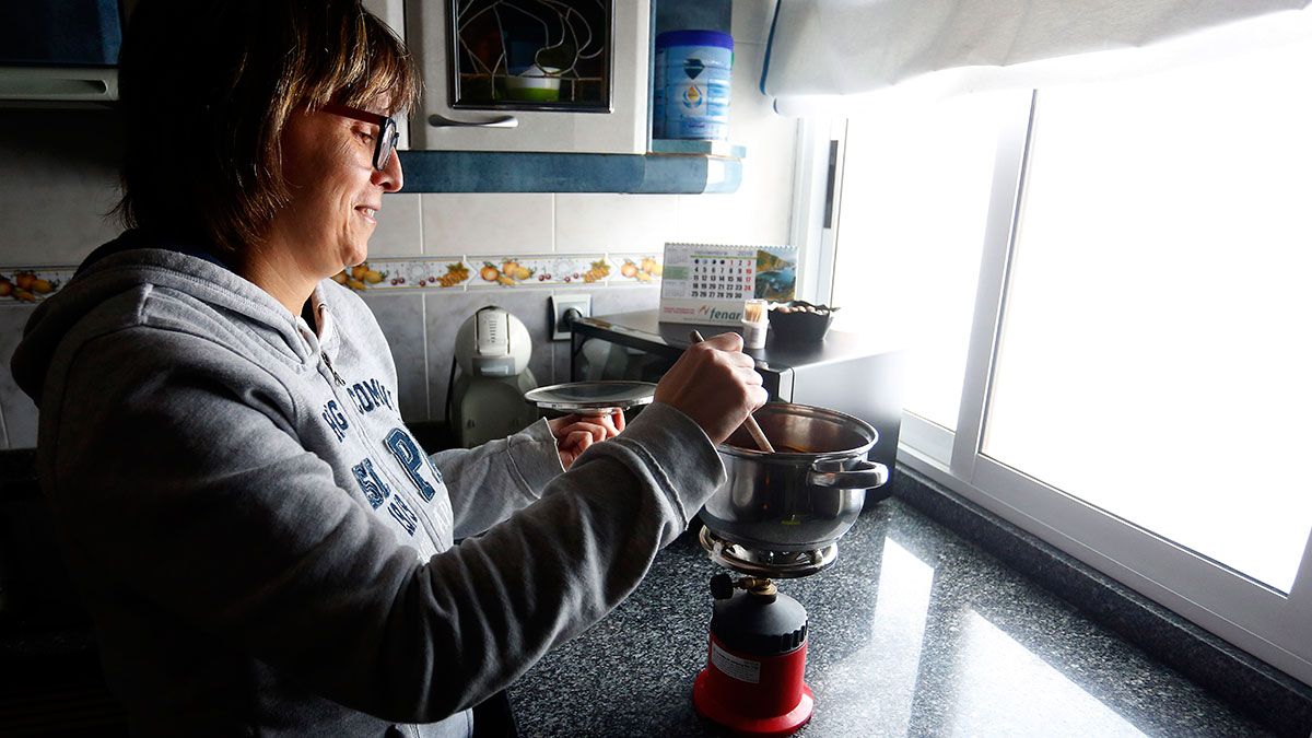 Una mujer en La Robla cocinando con un camping-gas ante la ausencia de luz. | ICAL