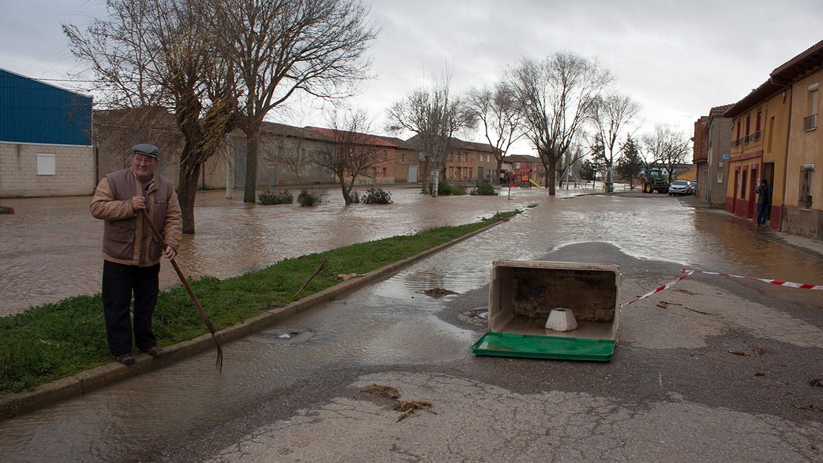 Un vecino de Cimanes de la Vega recoge con una horca los restos que el río dejó en la noche del viernes. | T.G.