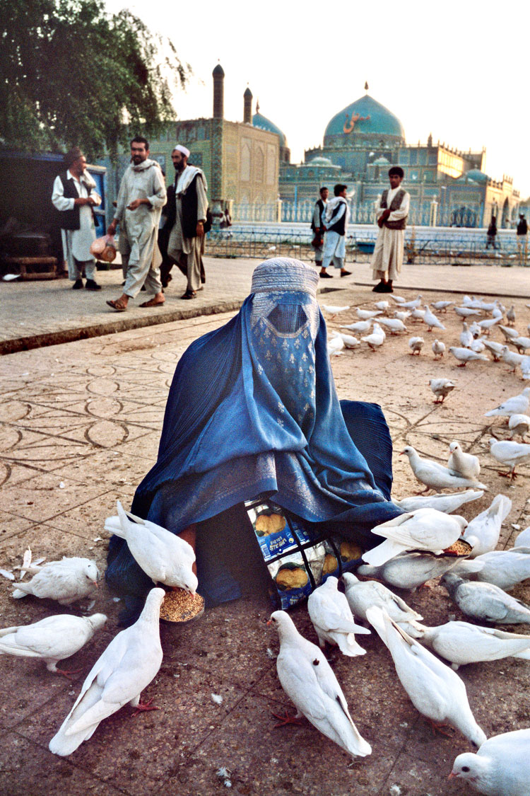 Una mujer afgana alimenta a las palomas en un parque al lado de la mezquita Hazrat Ali, en la ciudad santa de Mazar-E-Sharif. | JM LÓPEZ