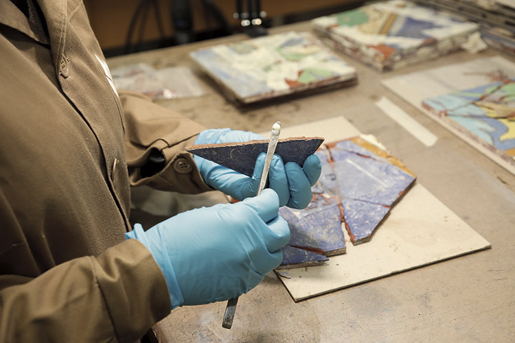La restauradora se dispone a pegar los azulejos fragmentados.