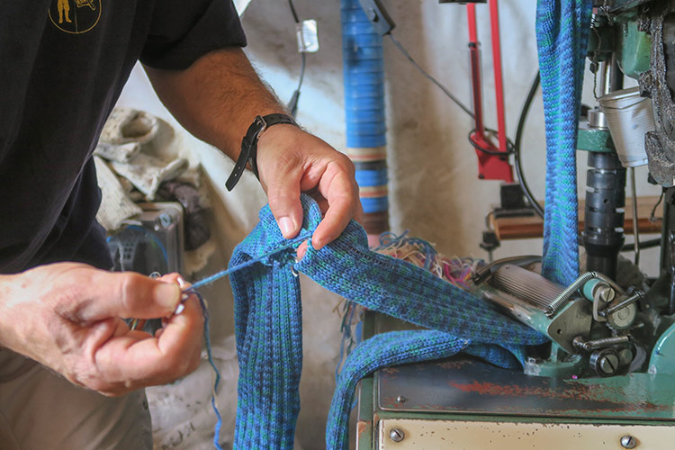 Santiago Geijo, responsable de la empresa de artesanía textil que lleva su nombe, recoge la tira calcetines que confecciona la maquina para después seleccionarlos uno a uno. | EDUARDO MARGARETO (ICAL)