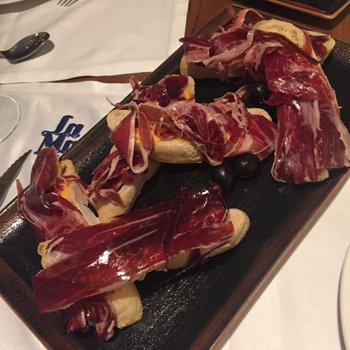 Seis piezas de paletilla de ibérico con pan, tomate y aceitunas negras. | S.M.